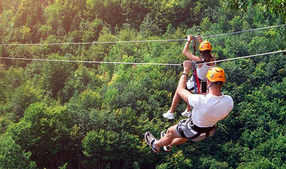 Zipline is an exciting adventure activity. Man and woman hanging on a rope-way. Tourists ride on the Zipline through the canyon of the Tara River Montenegro. Couple in helmets is riding on a cable car