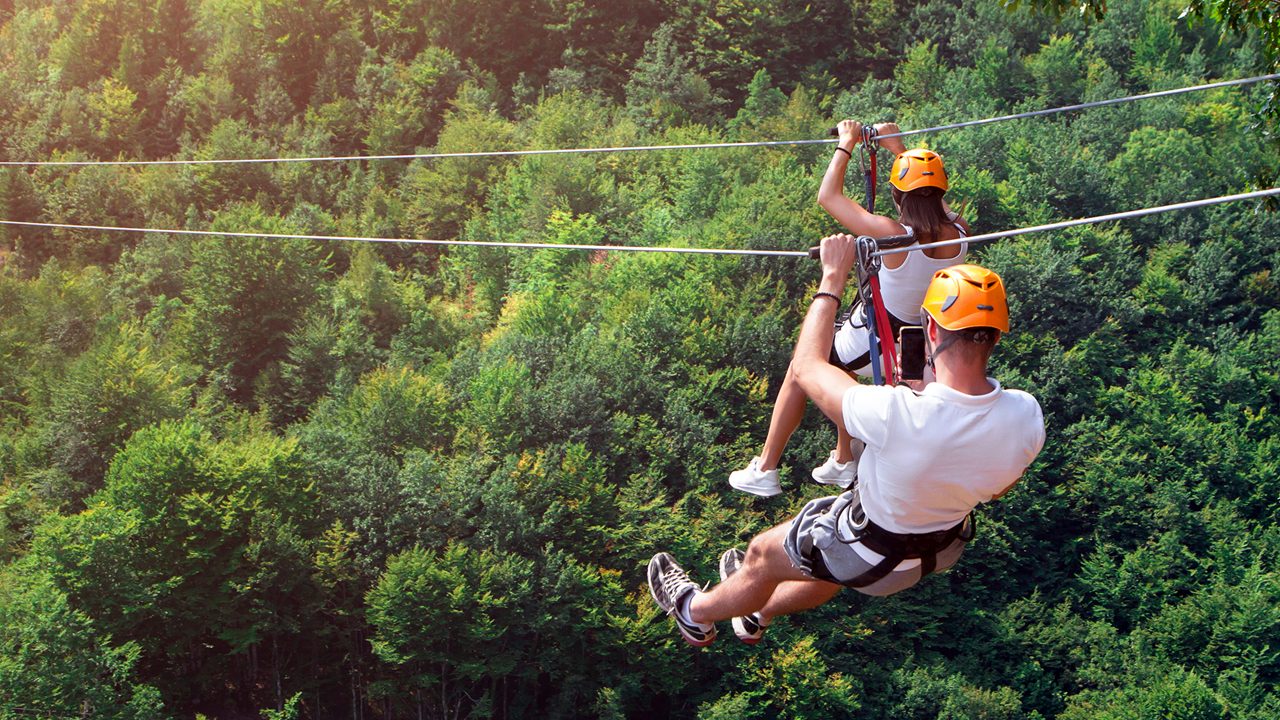 Zipline is an exciting adventure activity. Man and woman hanging on a rope-way. Tourists ride on the Zipline through the canyon of the Tara River Montenegro. Couple in helmets is riding on a cable car