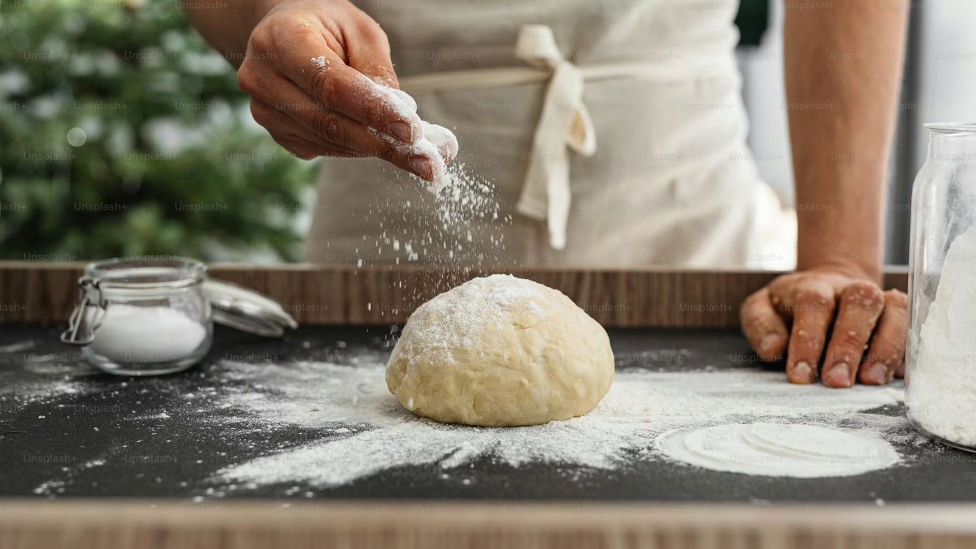Baker Sprinkling Flour Over Fresh Dough Ball