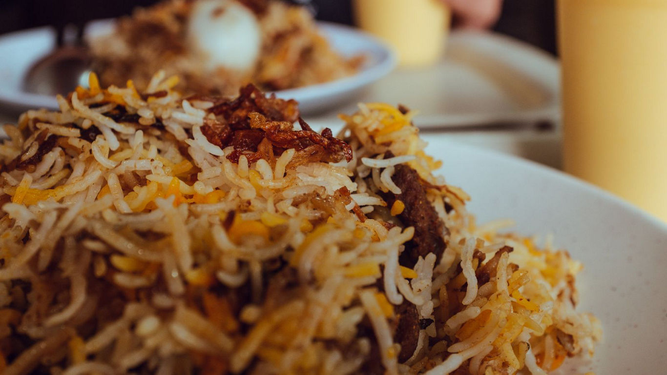 Aromatic Eid biryani served in a clay pot bowl with mint and fried onions on top.