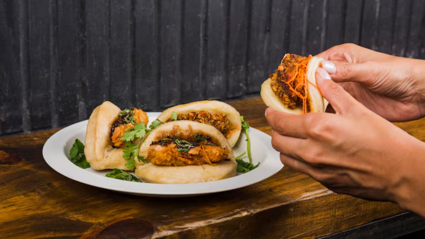 Hand holding stuffed bao buns on wooden table
