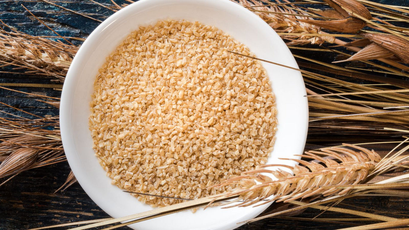 Bowl of bulgur wheat with grain stalks