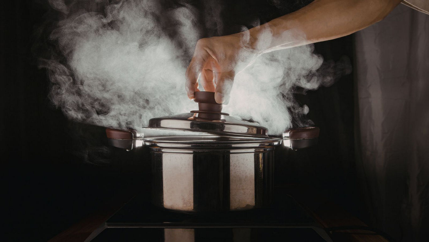 Hand Lifting Lid from Steaming Pot on Stove