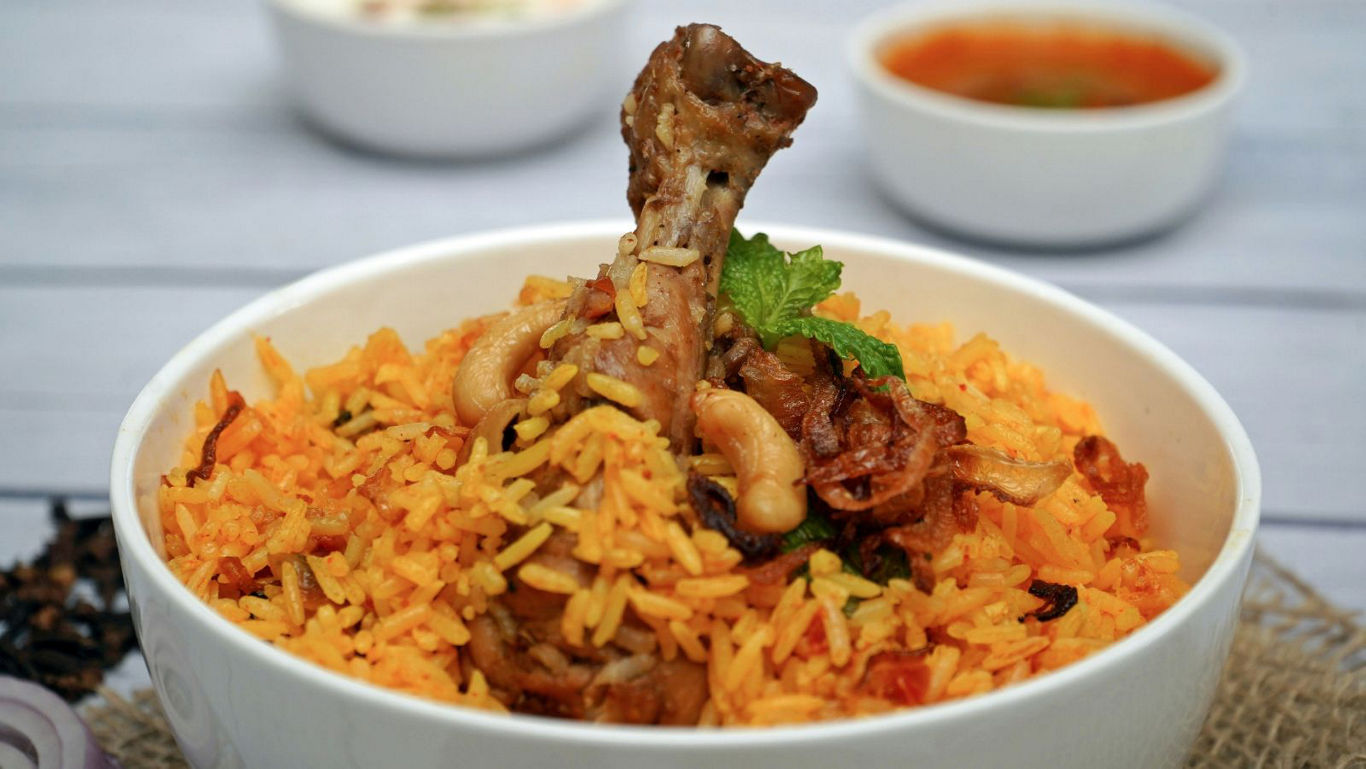 Chicken biryani served in white bowl with garnish