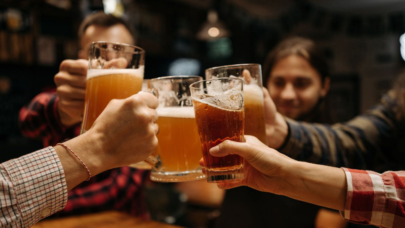 Group cheers with beer glasses in bar
