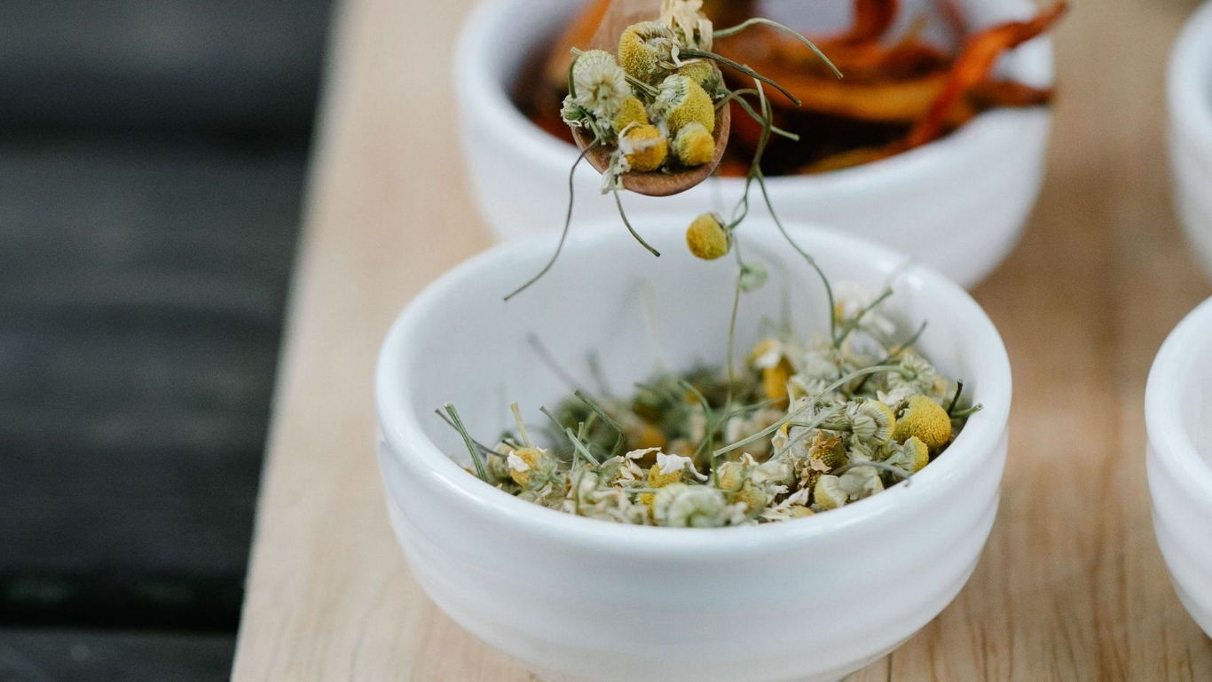 Dried chamomile flowers in white ceramic bowls