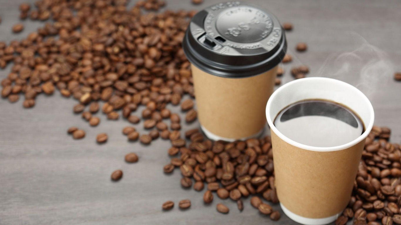 Hot coffee in disposable cups with beans
