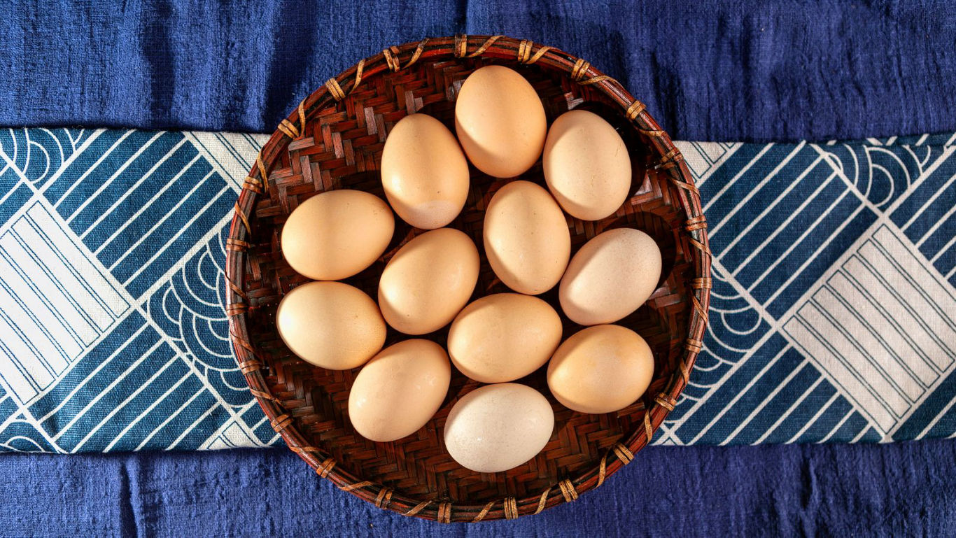 Brown eggs in woven basket on fabric
