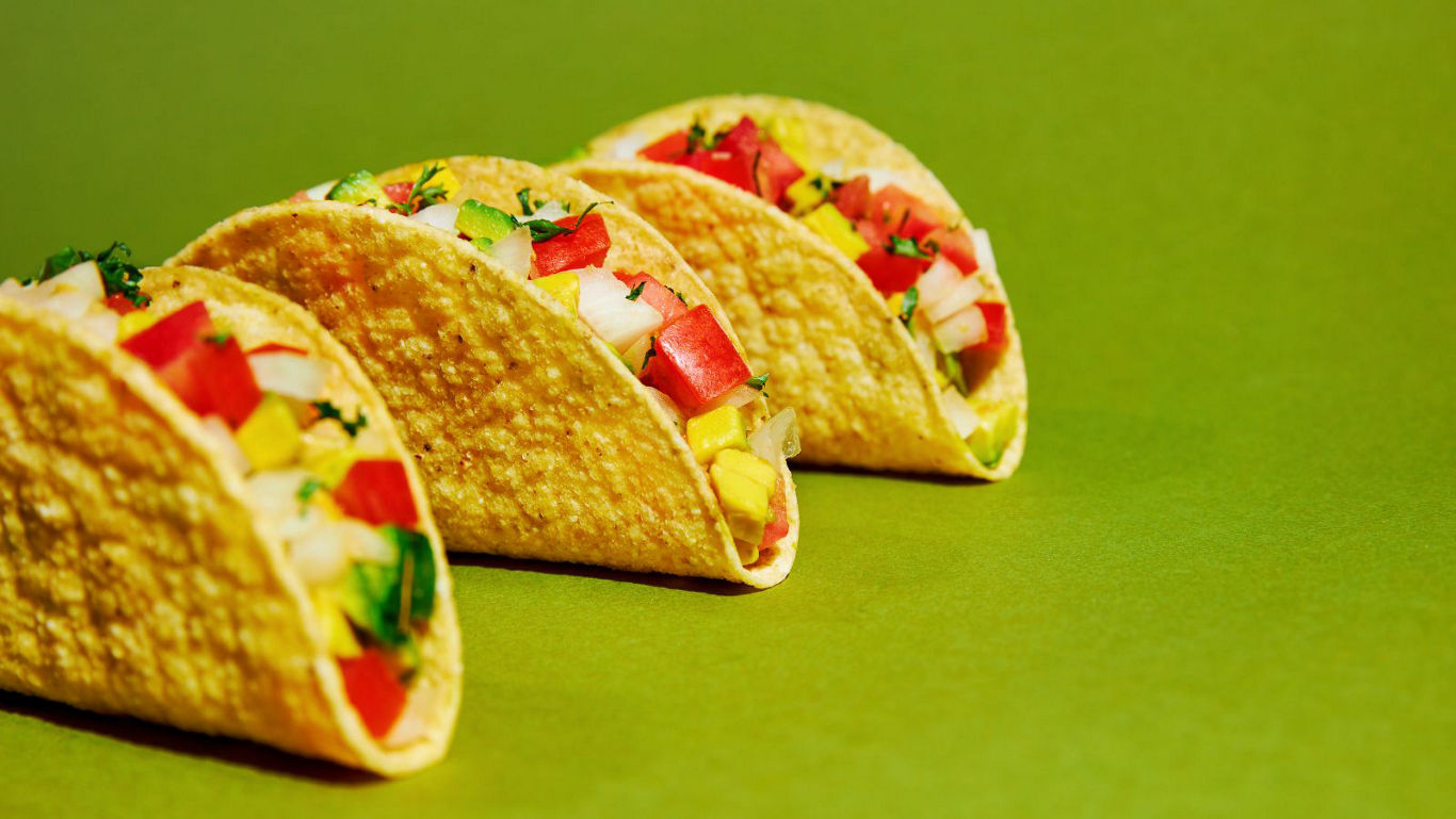 Row of colorful vegetable tacos on green