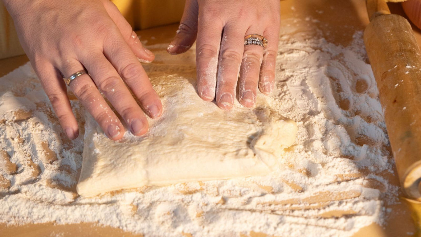 Hands kneading dough on floured surface