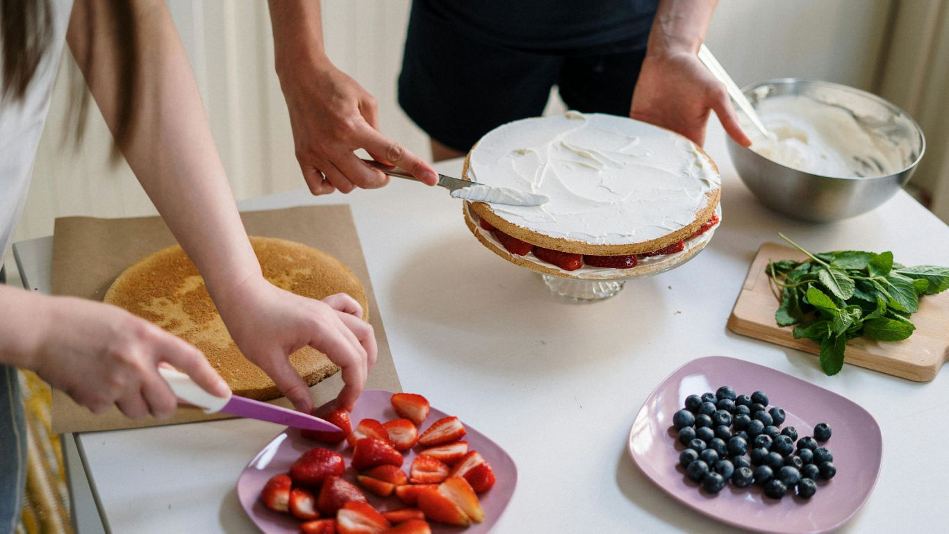Family decorating homemade berry layer cake