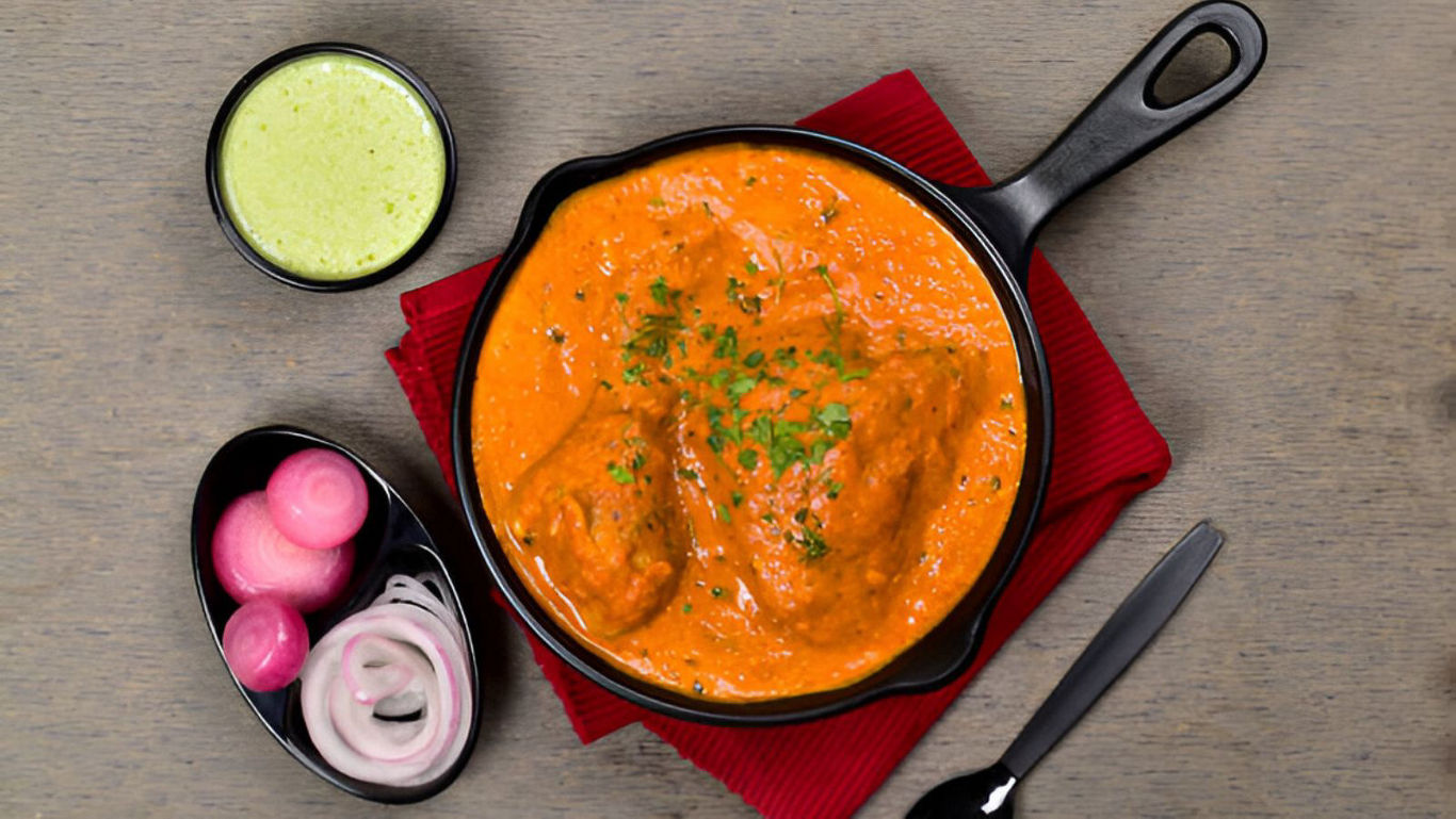 Butter chicken curry in skillet with sides