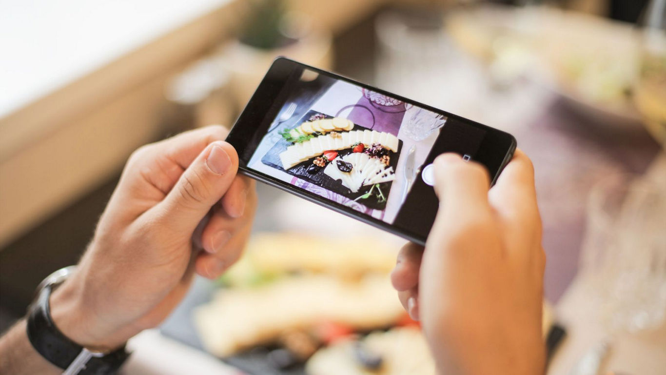 Person photographing gourmet meal with smartphone