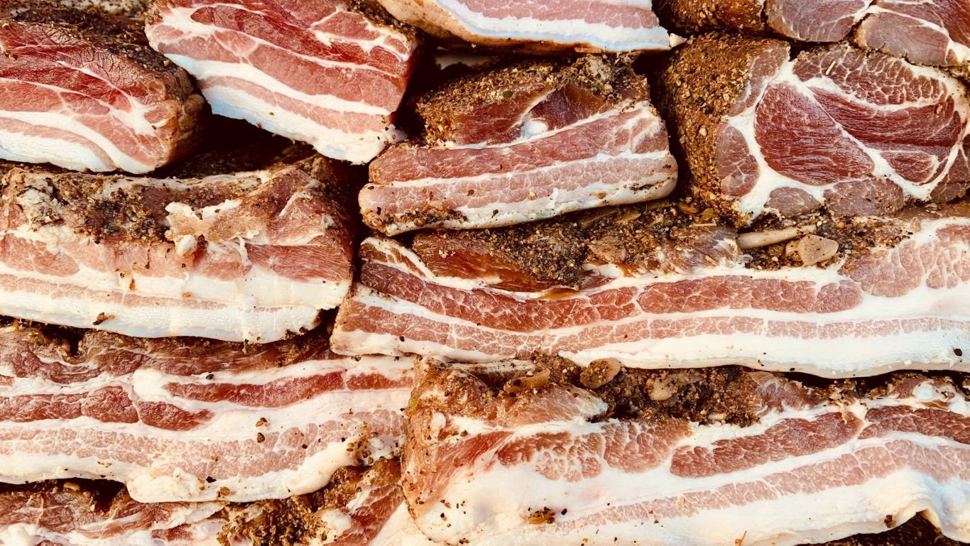 Stacked seasoned bacon slices close up