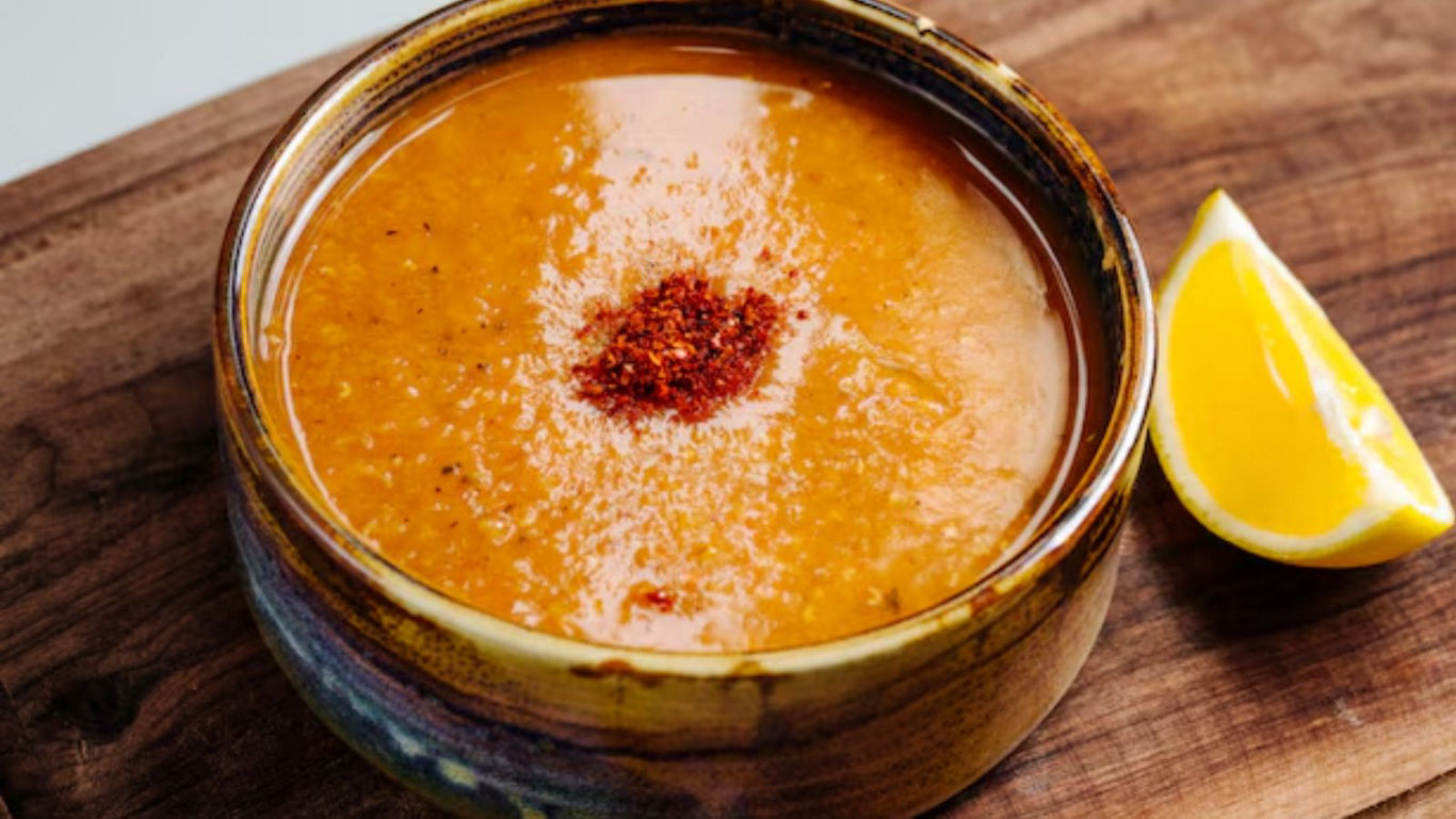 Bowl of lentil soup with lemon wedge on wood