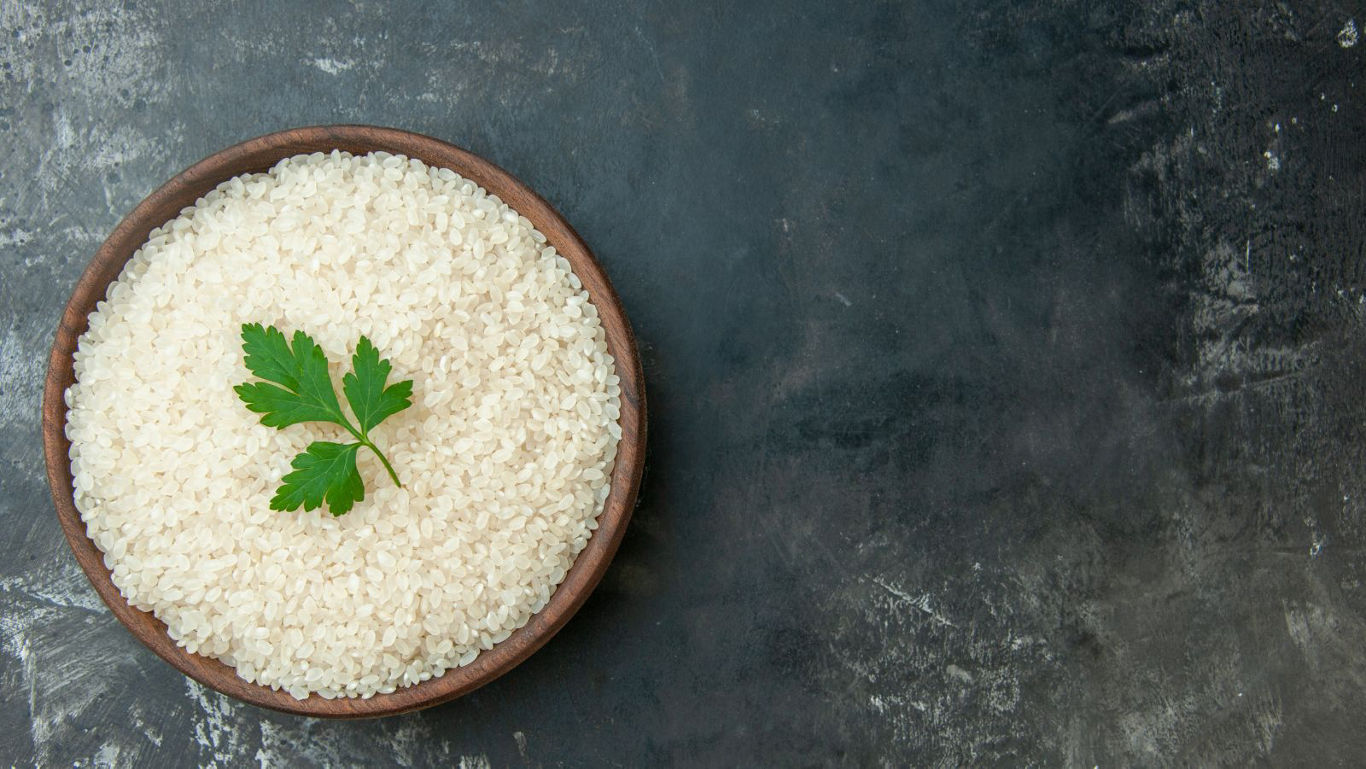 Bowl of raw white rice on slate