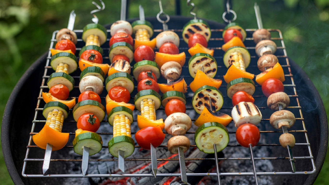 Colorful vegetable skewers grilling over charcoal