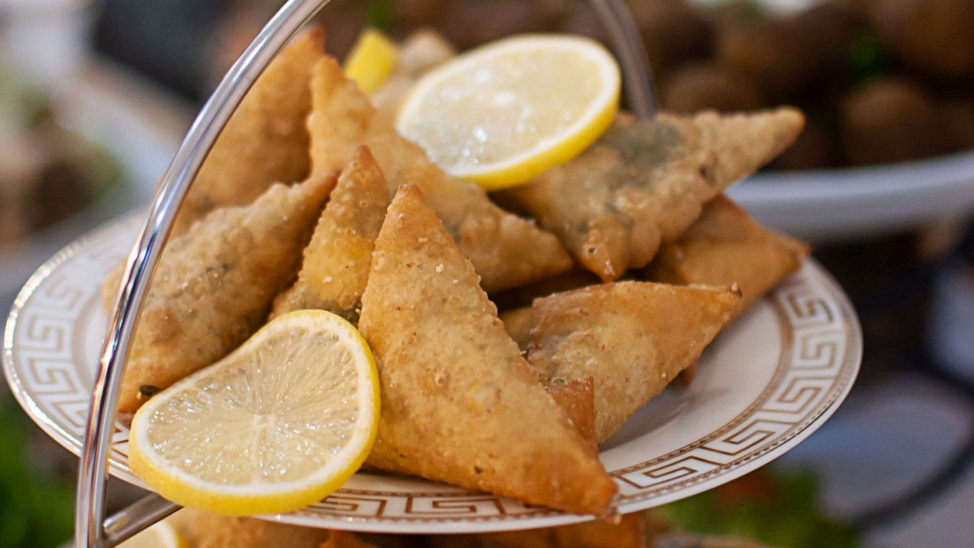 Golden fried samosas with lemon slices