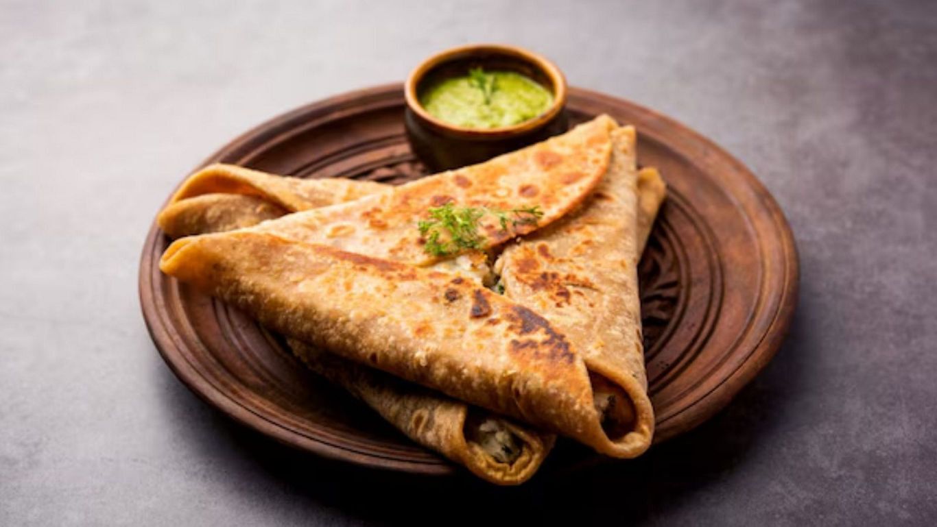 Stuffed paratha served with green chutney on plate