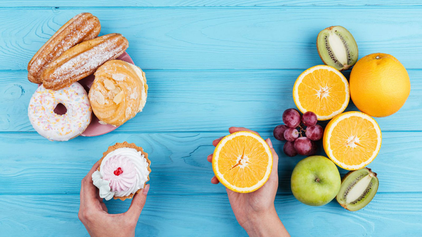 Hands Choosing Between Pastries And Fresh Fruit