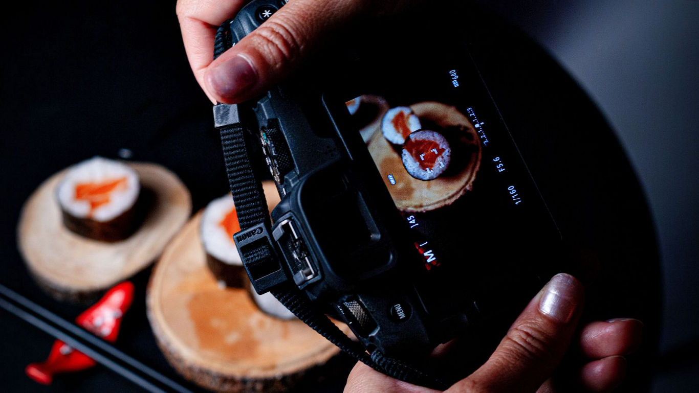 Photographer capturing sushi on wooden slices