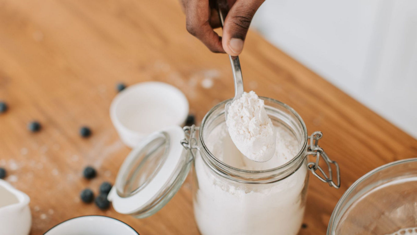 Hand scooping flour from glass jar
