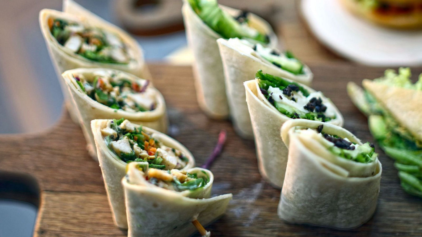 Fresh vegetable tortilla wraps on wooden board