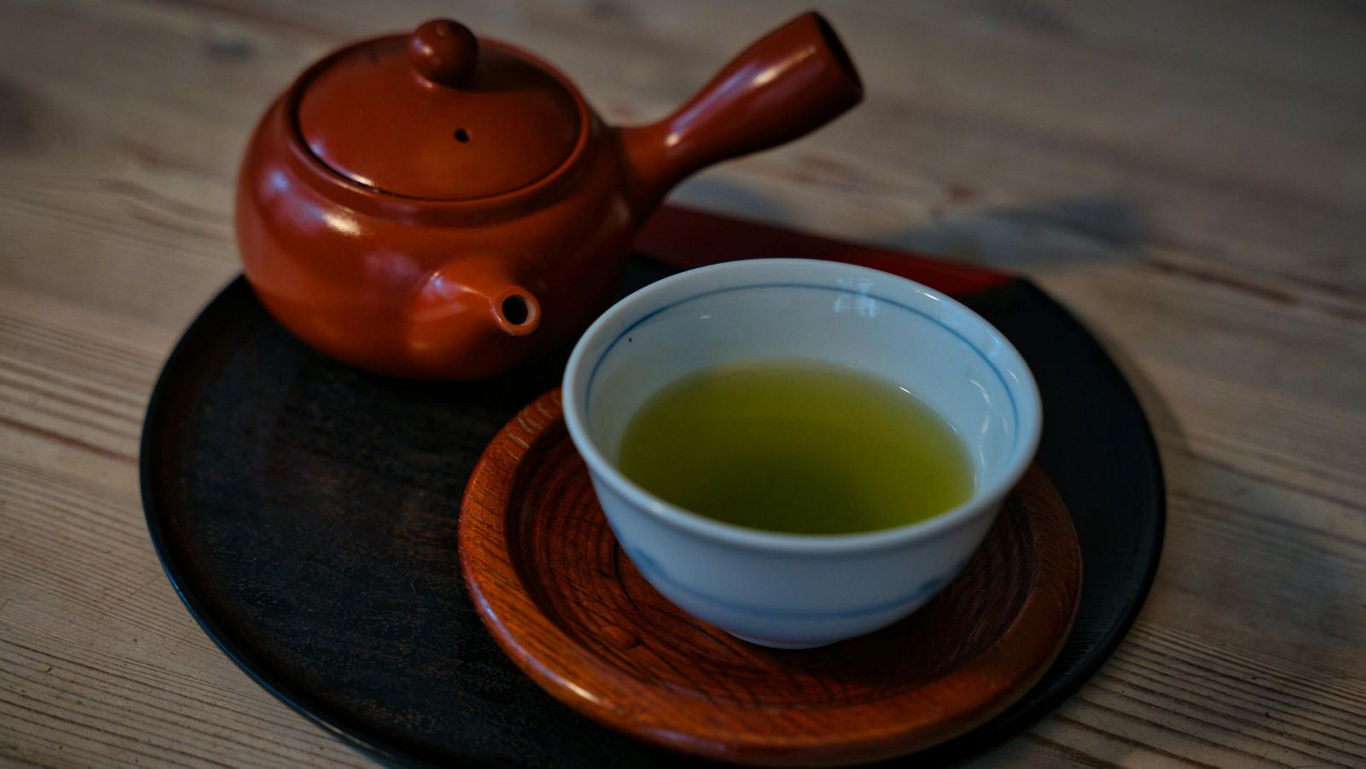 Cup of green tea with clay teapot