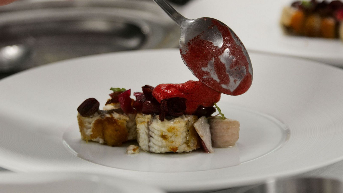 Chef plating gourmet dessert with sauce