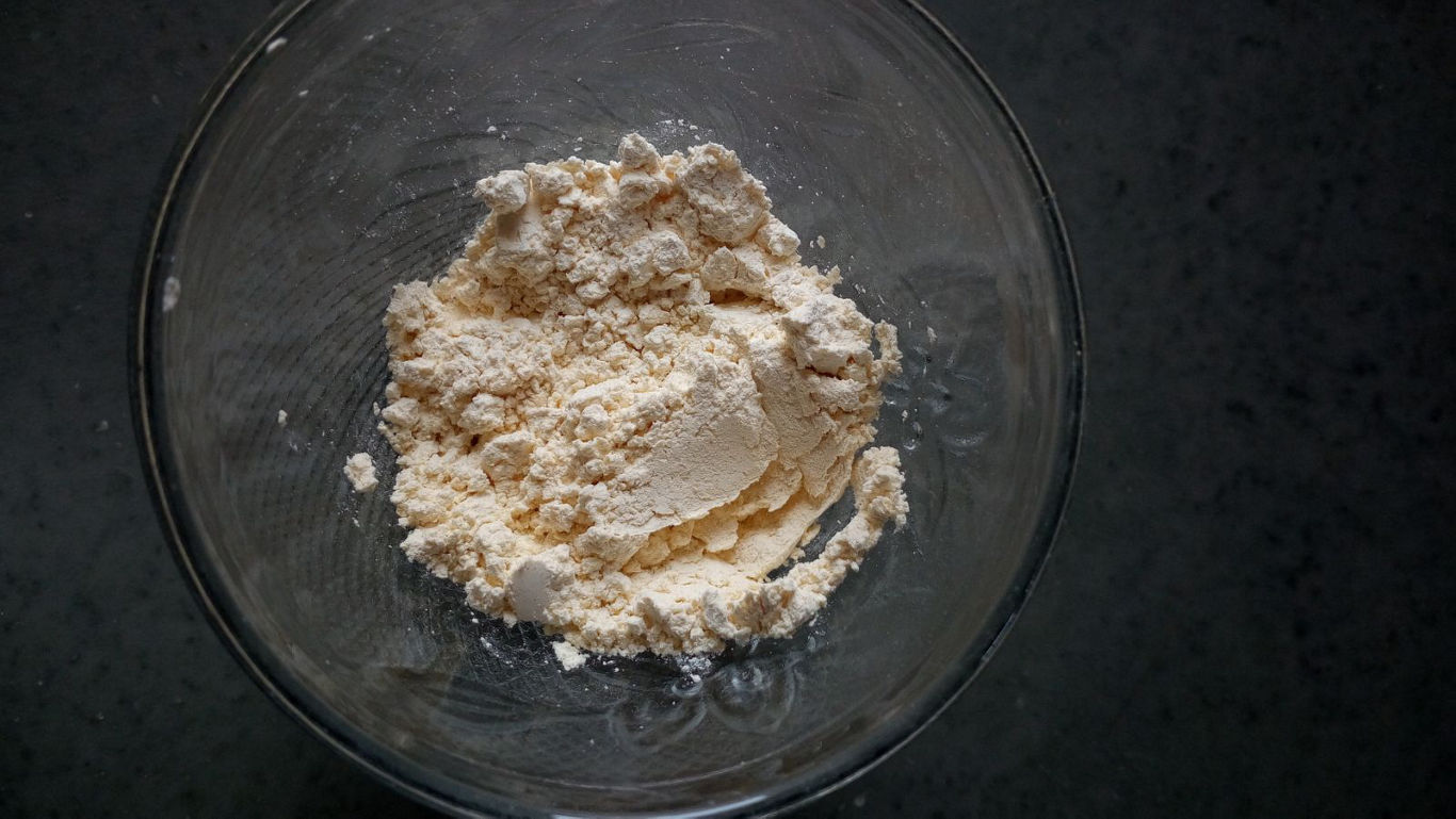 Bowl of dry flour on dark surface