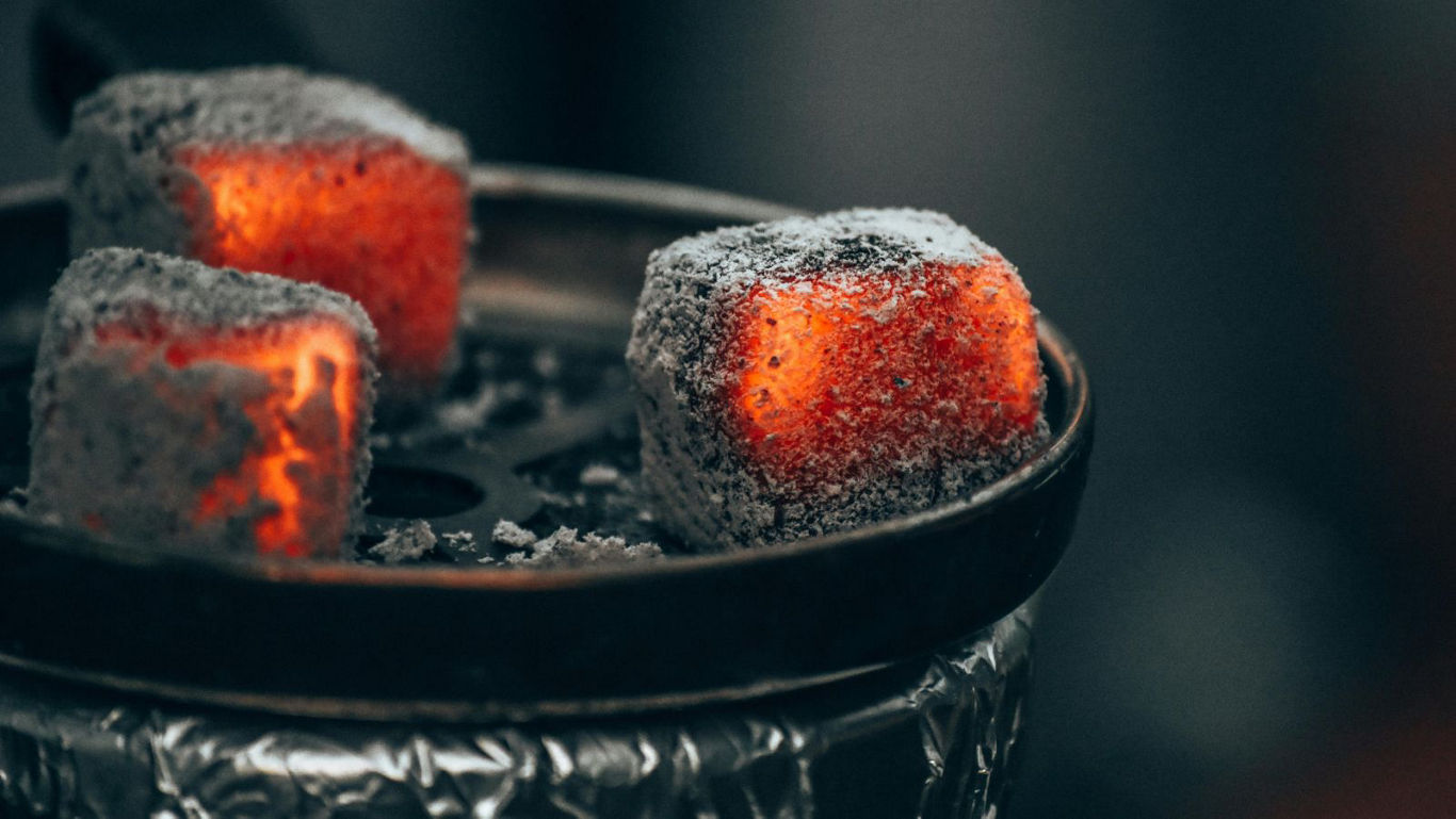 Glowing charcoal cubes on metal tray