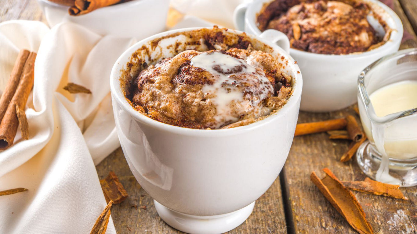 Cinnamon Mug Cake with Icing on Rustic Table