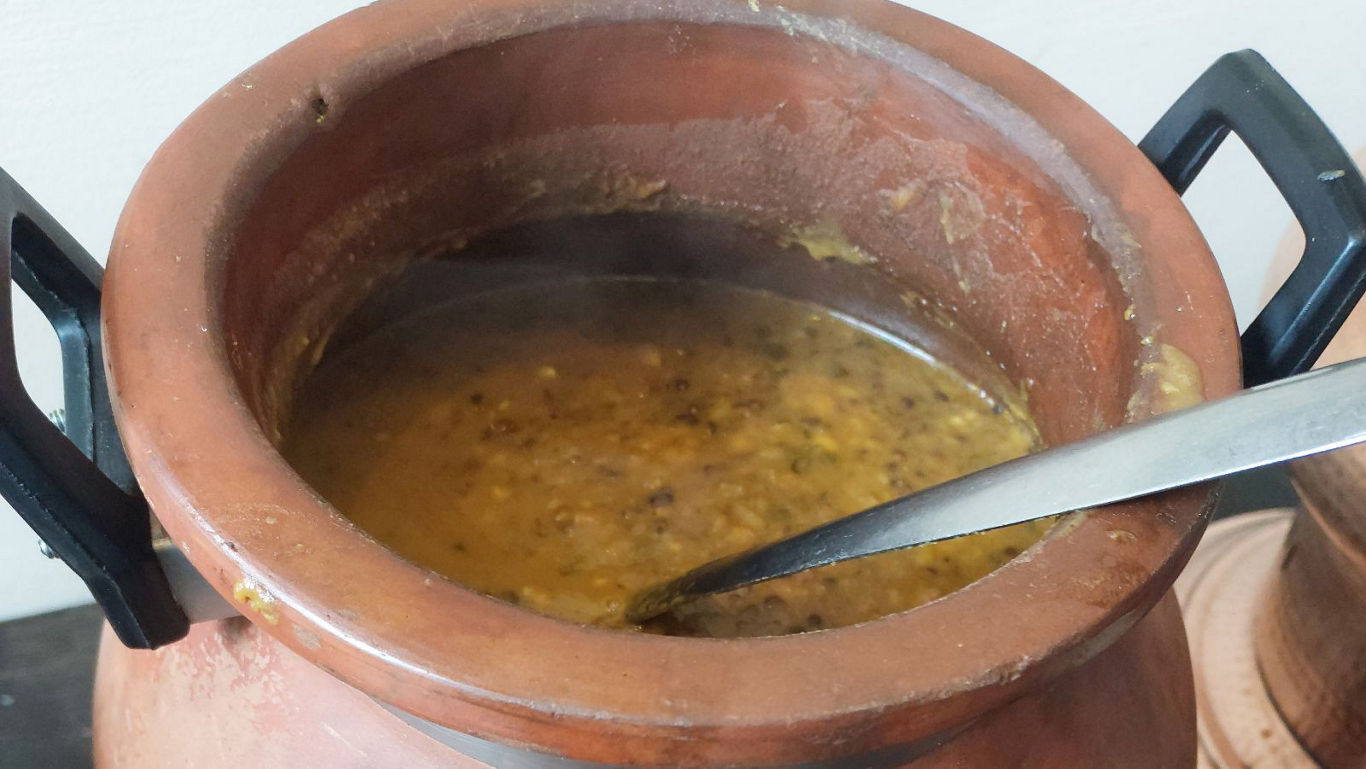 Traditional clay pot of simmering lentil curry