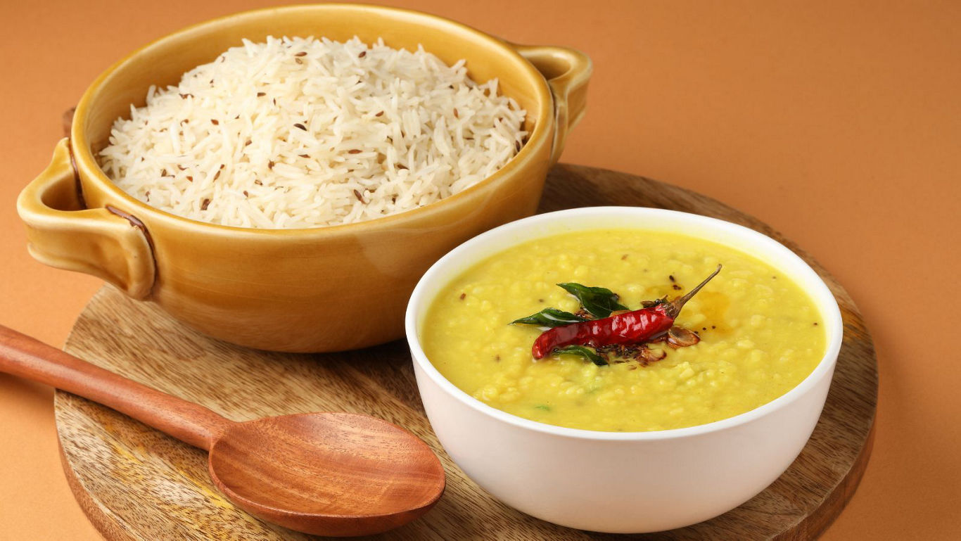 Bowl of dal with rice on wooden board