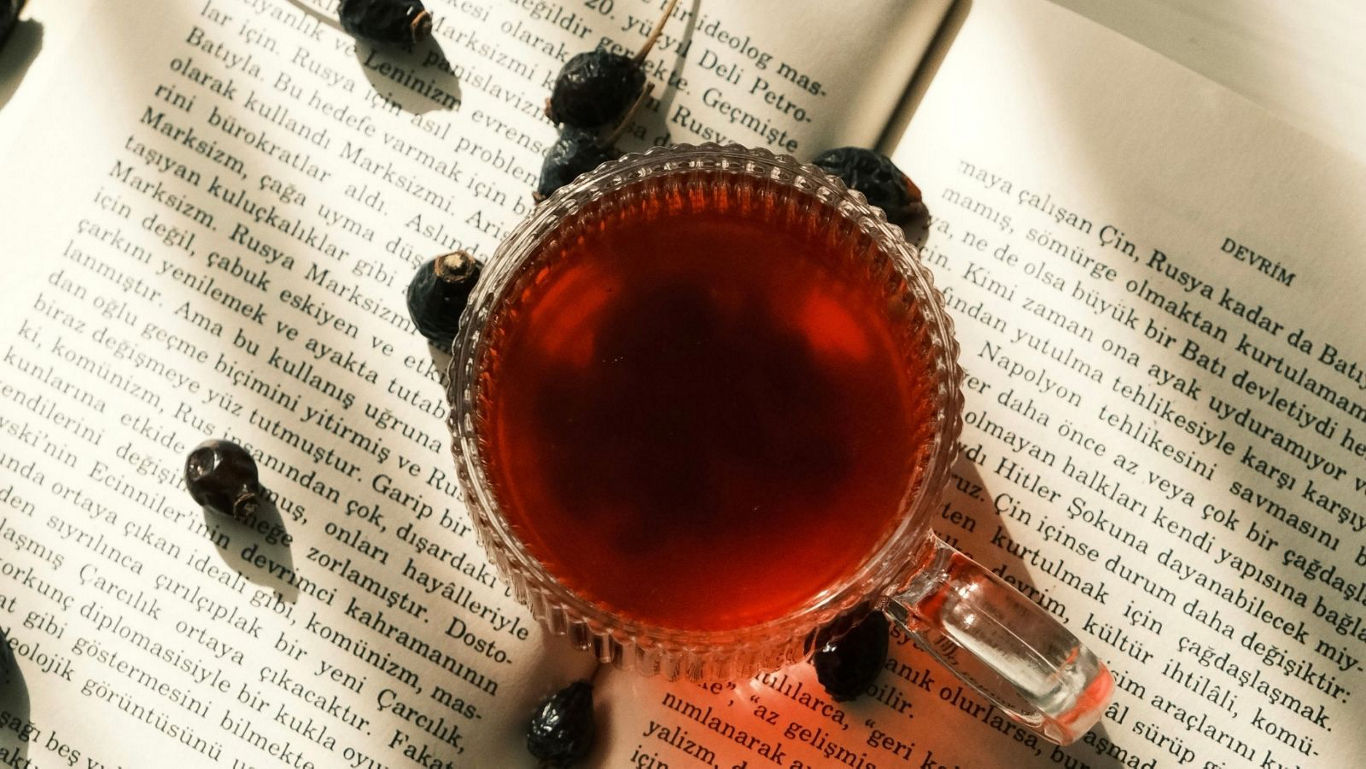 Glass cup of tea on open book