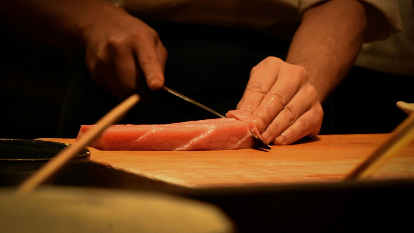 Chef slicing fresh tuna on wooden board
