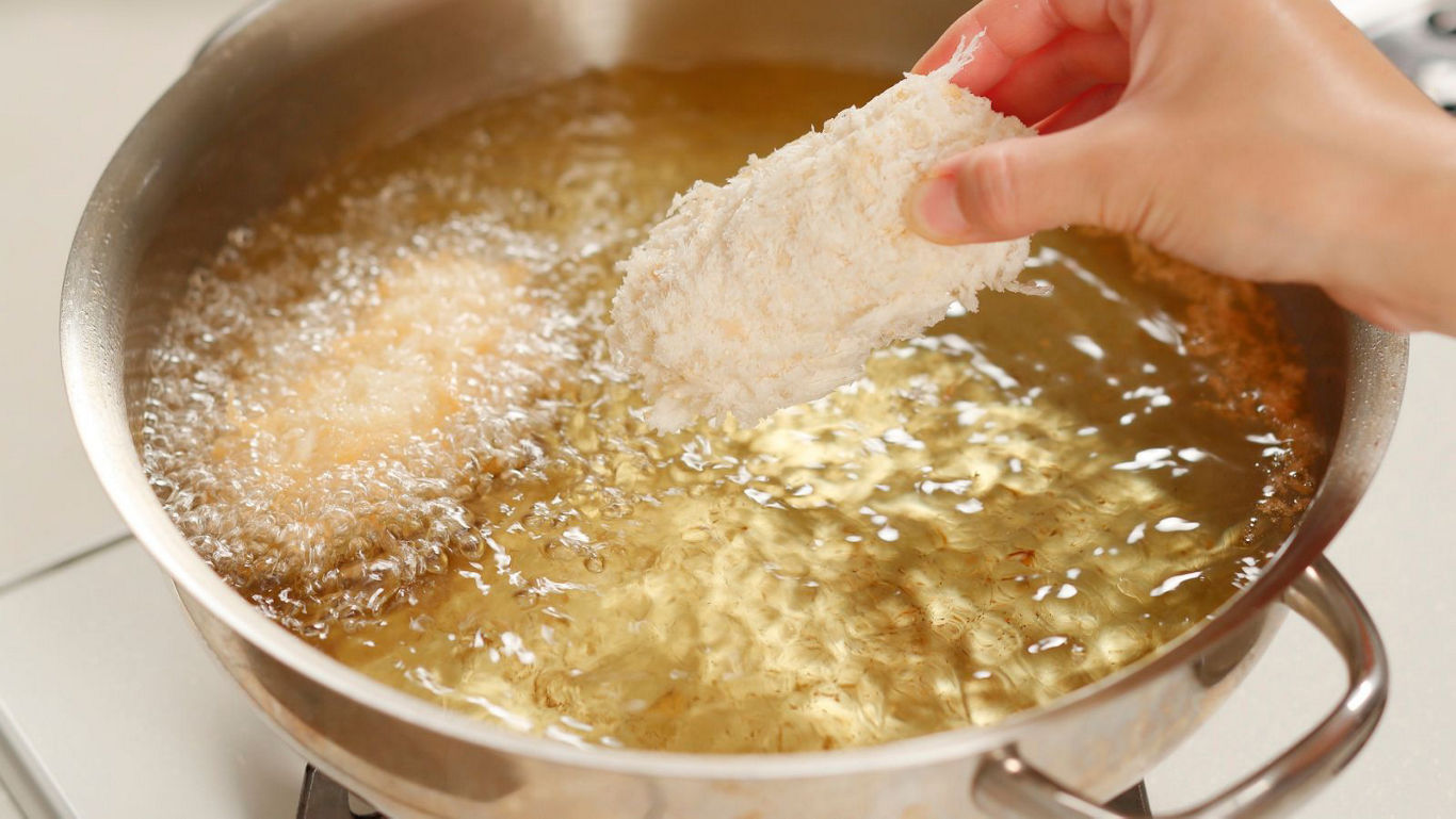 Hand breading cutlet before deep frying in pan