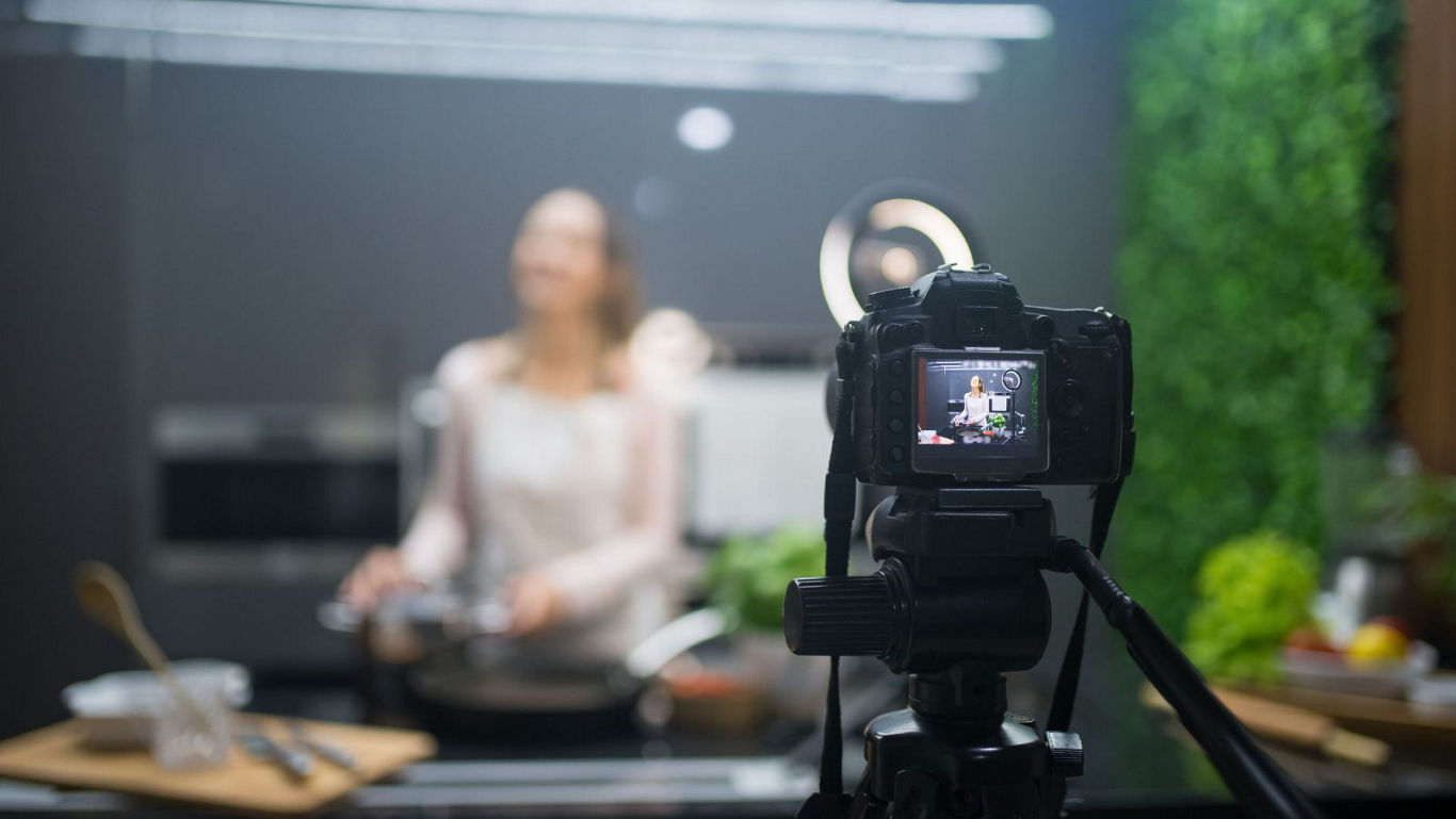 Camera filming woman cooking in kitchen studio