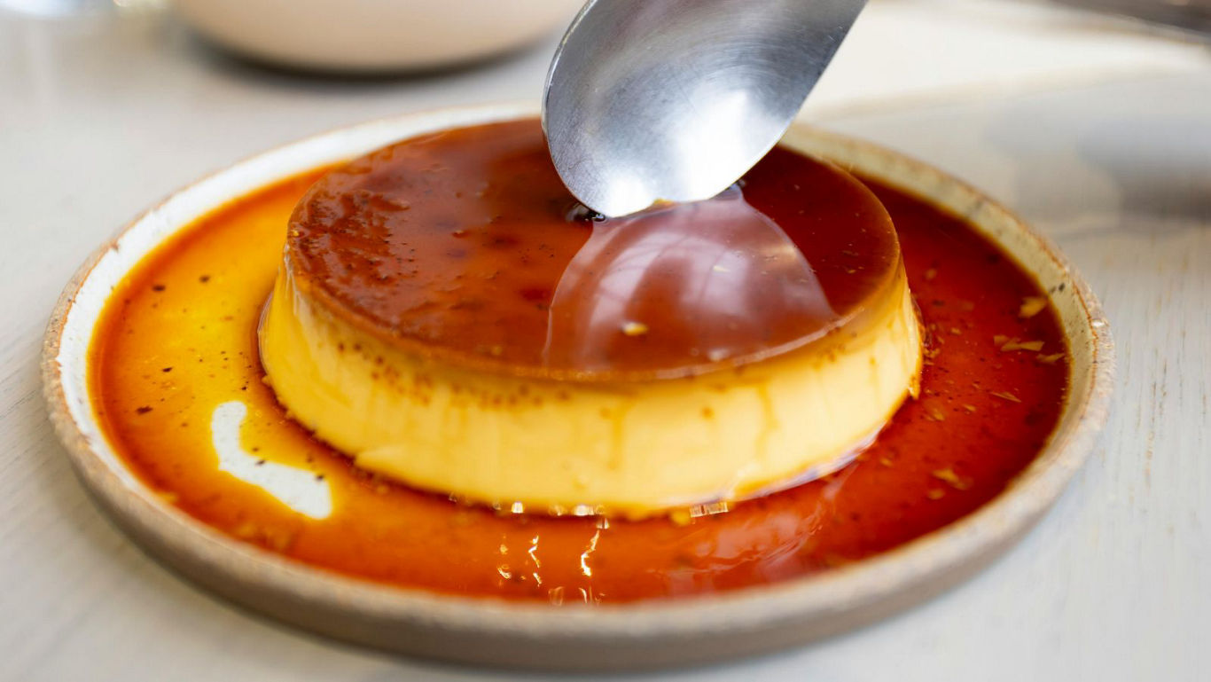 Spoon scooping creamy caramel flan dessert