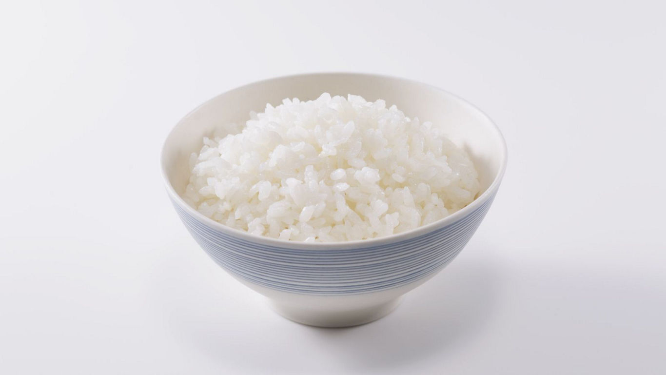 Steaming bowl of white rice on white background