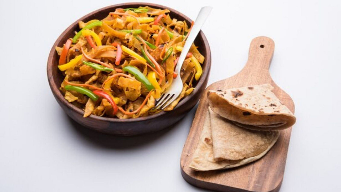 Colorful stir-fried vegetables with flatbread on board