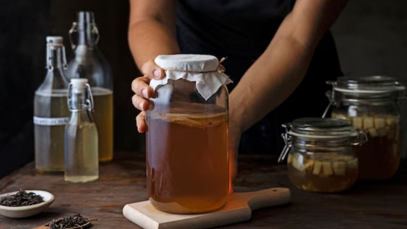 Person preparing homemade kombucha in glass jars