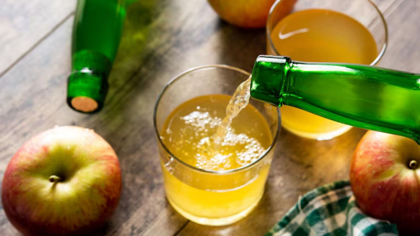 Pouring apple cider into glass on table