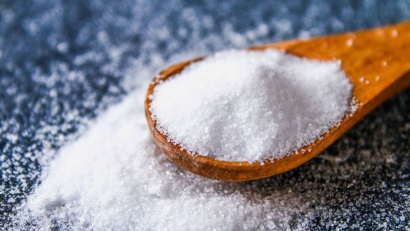 Wooden spoon filled with white granulated salt