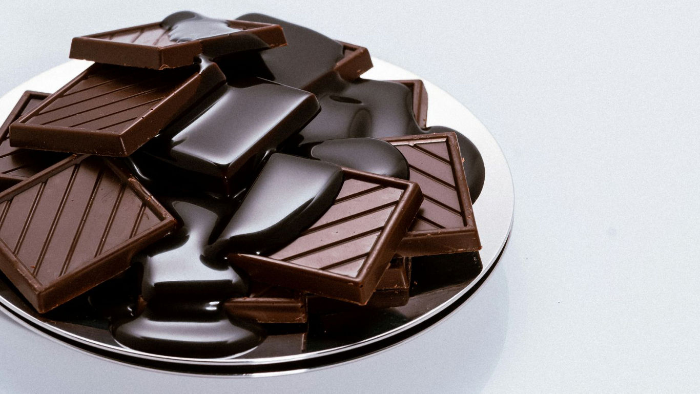 Dark chocolate pieces melting on silver plate