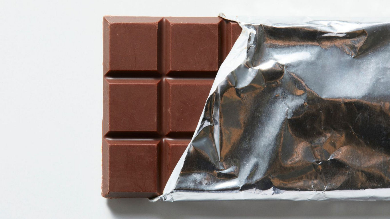 Partially unwrapped milk chocolate bar closeup