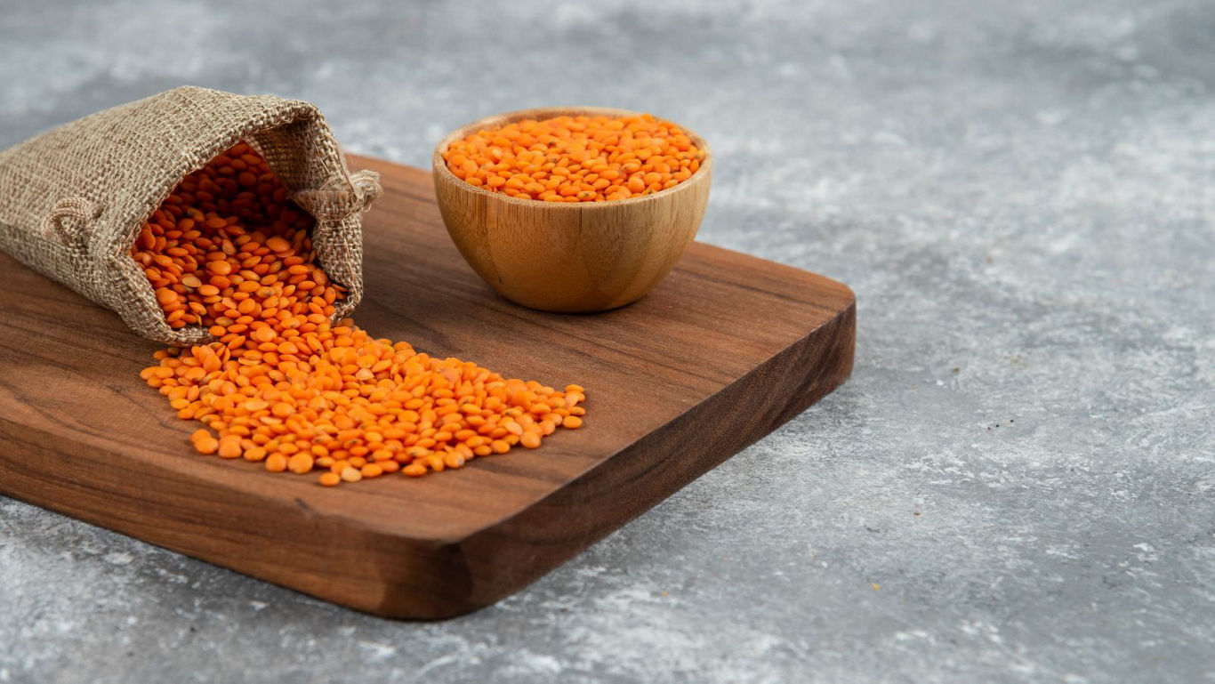 Red lentils spilling from burlap sack