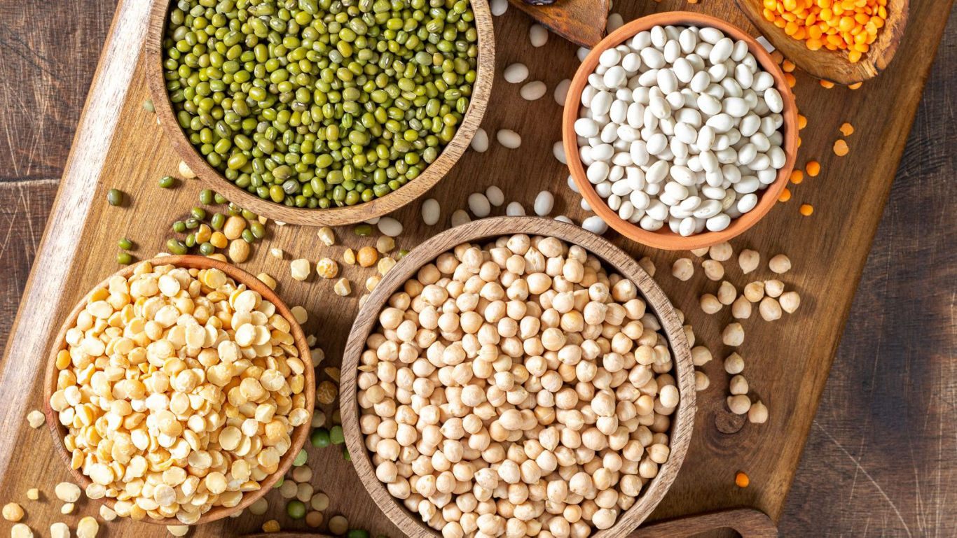 Assorted legumes in wooden bowls on table