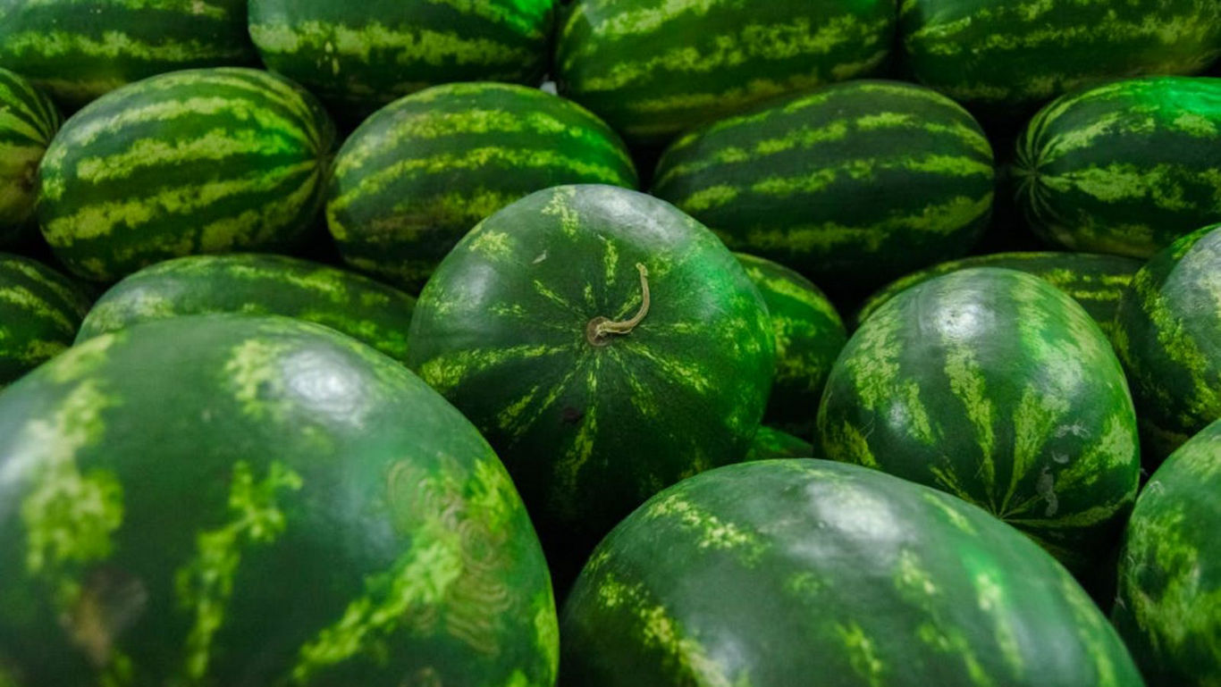 Fresh whole watermelons stacked in bulk display