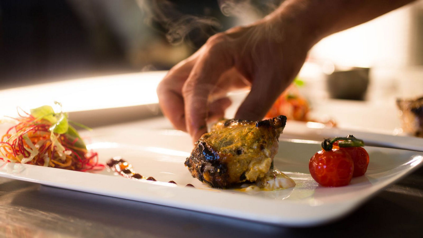 Chef plating gourmet roasted meat dish